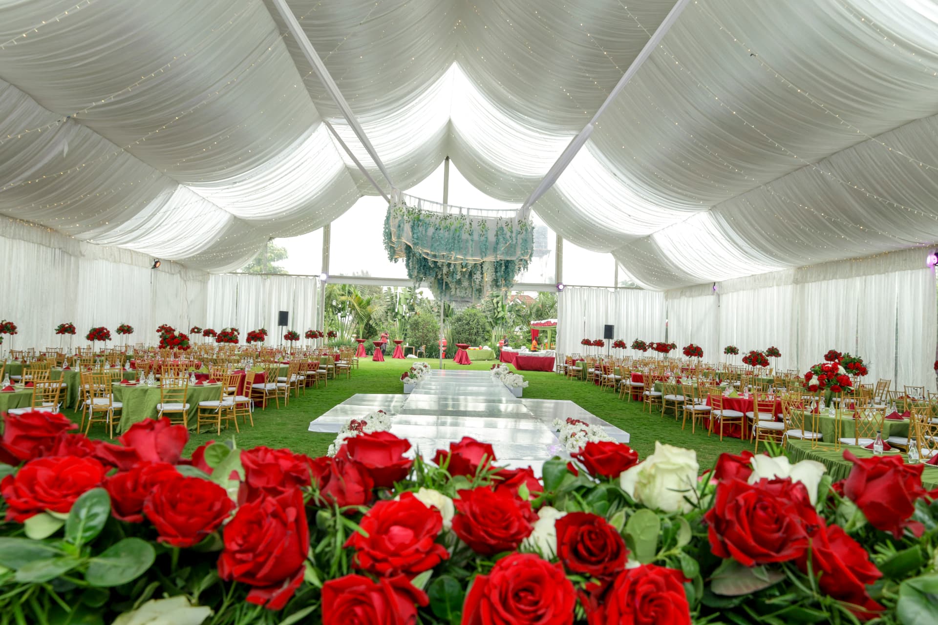 Elegant white marquee reception with red roses, gold chairs and a central dance floor