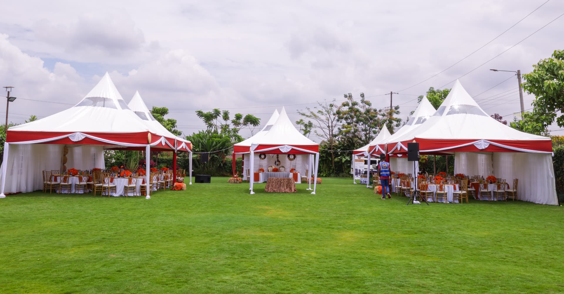 Spacious green lawn arranged with red and white event canopies