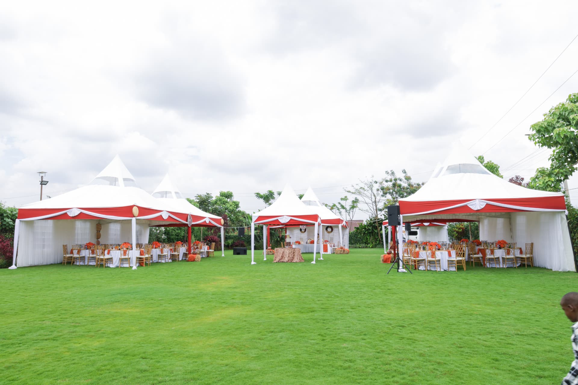 Wide green event lawn framed by red and white canopies
